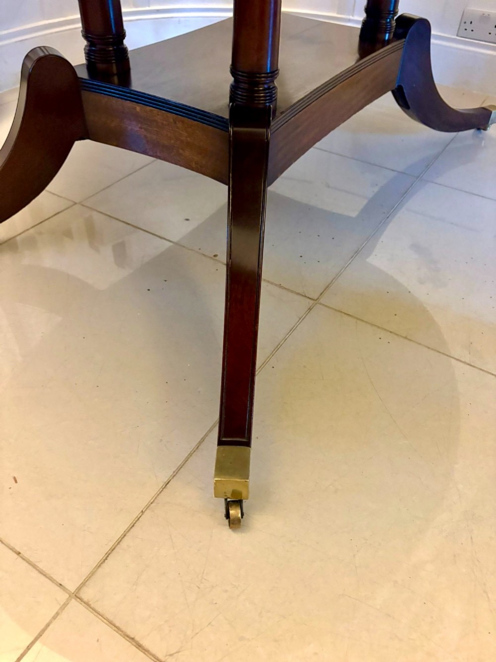 An antique oval extending mahogany dining table on splayed pedestal legs with brass castors. View XII