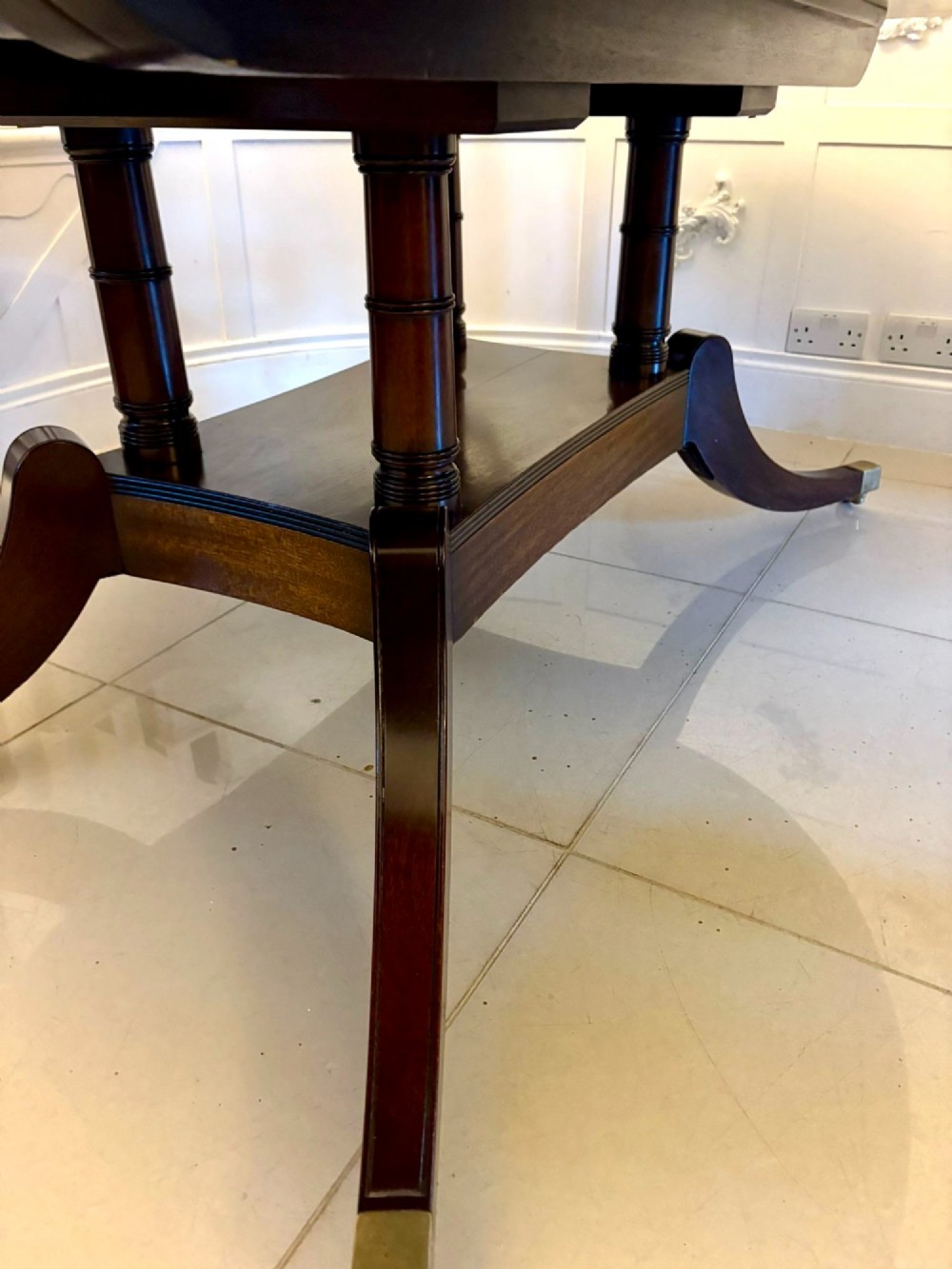 An antique oval extending mahogany dining table on splayed pedestal legs with brass castors. View XIII
