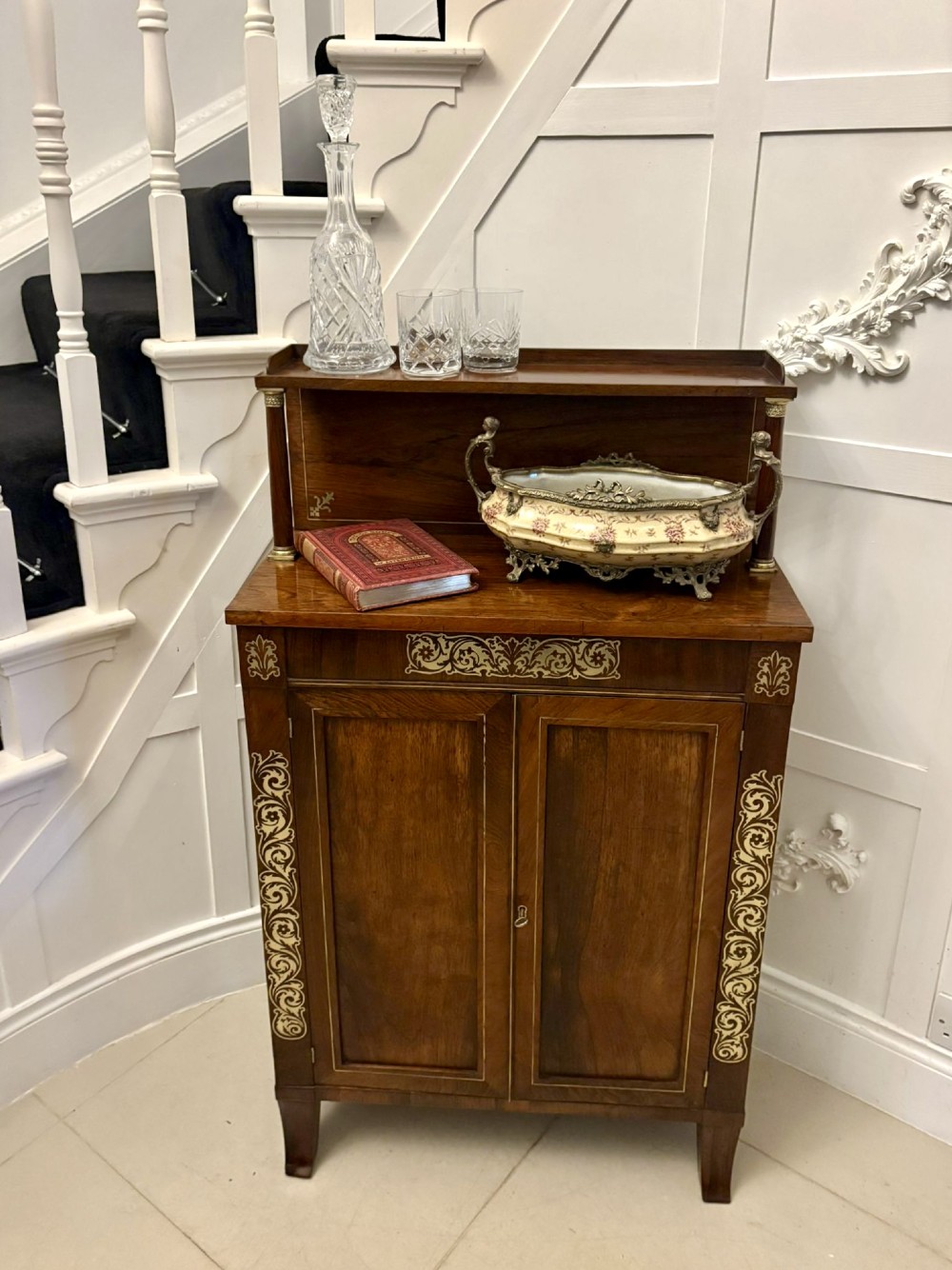An antique Regency mahogany chiffonier side cabinet featuring intricate floral brass inlay on the doors and frieze with an upper open shelf. View V