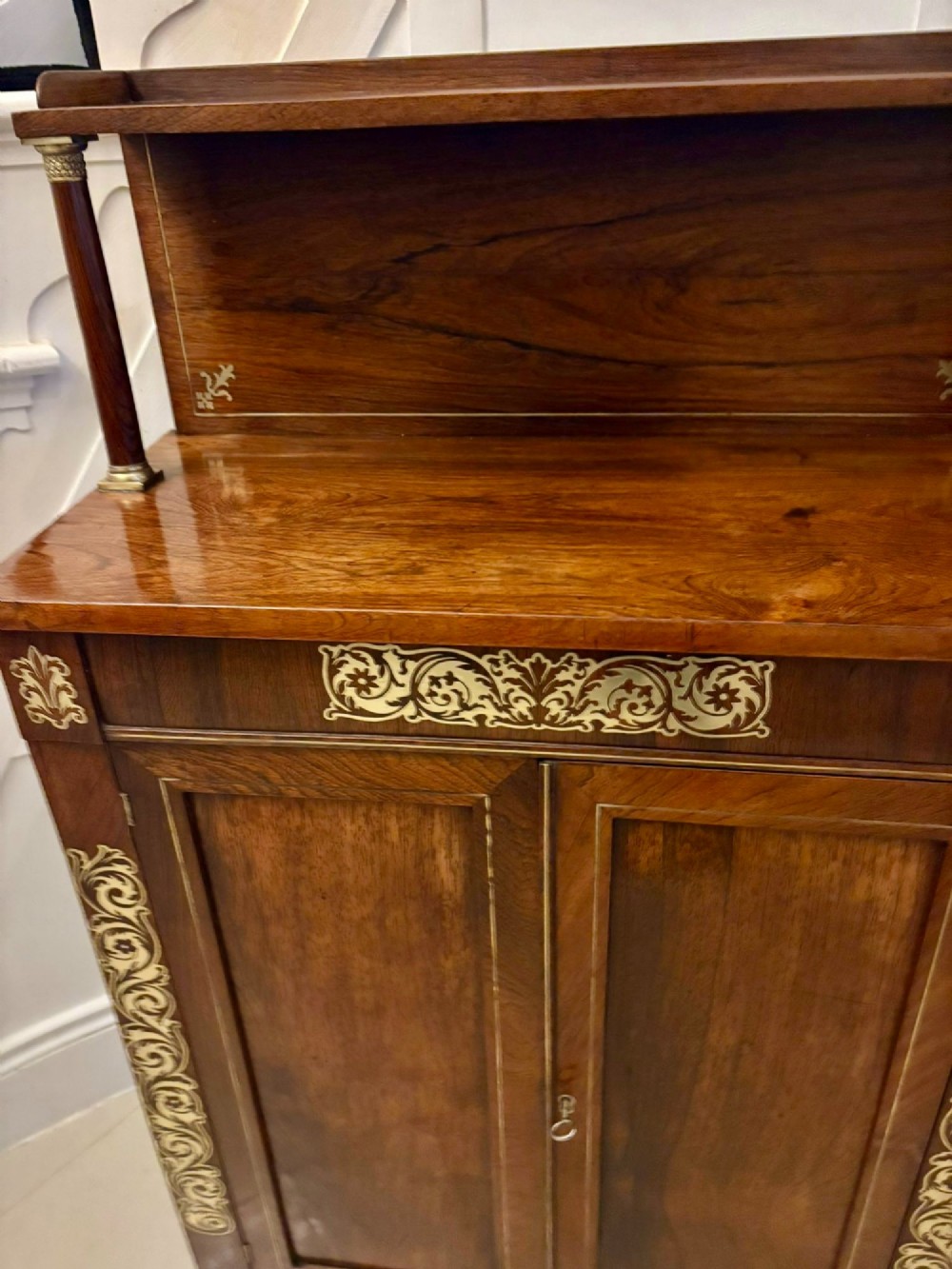 An antique Regency mahogany chiffonier side cabinet featuring intricate floral brass inlay on the doors and frieze with an upper open shelf. View VI
