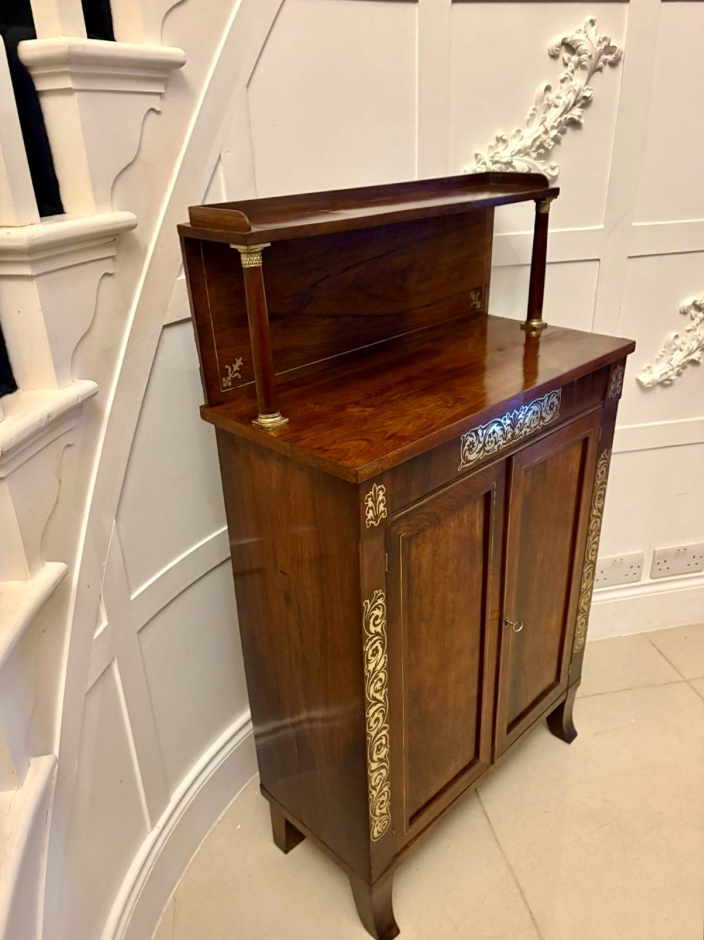 An antique Regency mahogany chiffonier side cabinet featuring intricate floral brass inlay on the doors and frieze with an upper open shelf. View VIII
