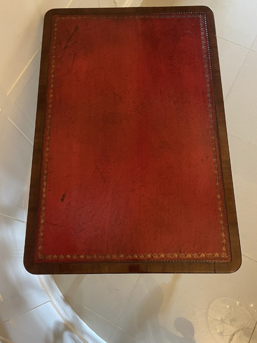 An antique Regency mahogany free-standing writing desk featuring a red leather gilt-tooled insert, two frieze drawers, lyre-form end supports, and brass castors. View X