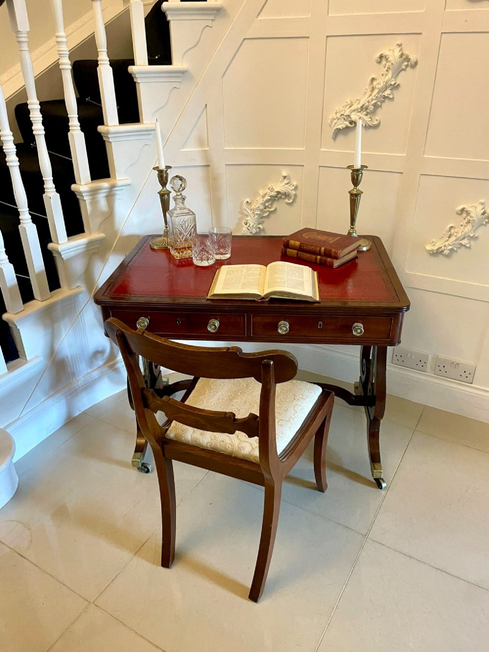 An antique Regency mahogany free-standing writing desk featuring a red leather gilt-tooled insert, two frieze drawers, lyre-form end supports, and brass castors. View XI