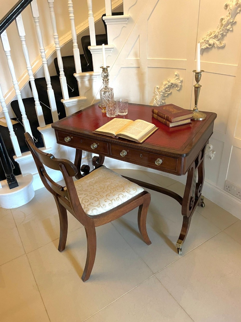An antique Regency mahogany free-standing writing desk featuring a red leather gilt-tooled insert, two frieze drawers, lyre-form end supports, and brass castors. View XIV