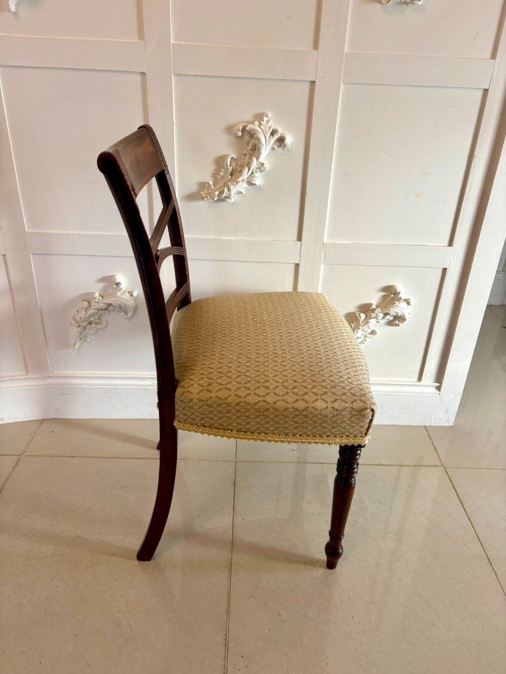 A set of eight George III style mahogany dining chairs featuring two carvers and six side chairs with reeded frames and patterned cream upholstered seats. View V