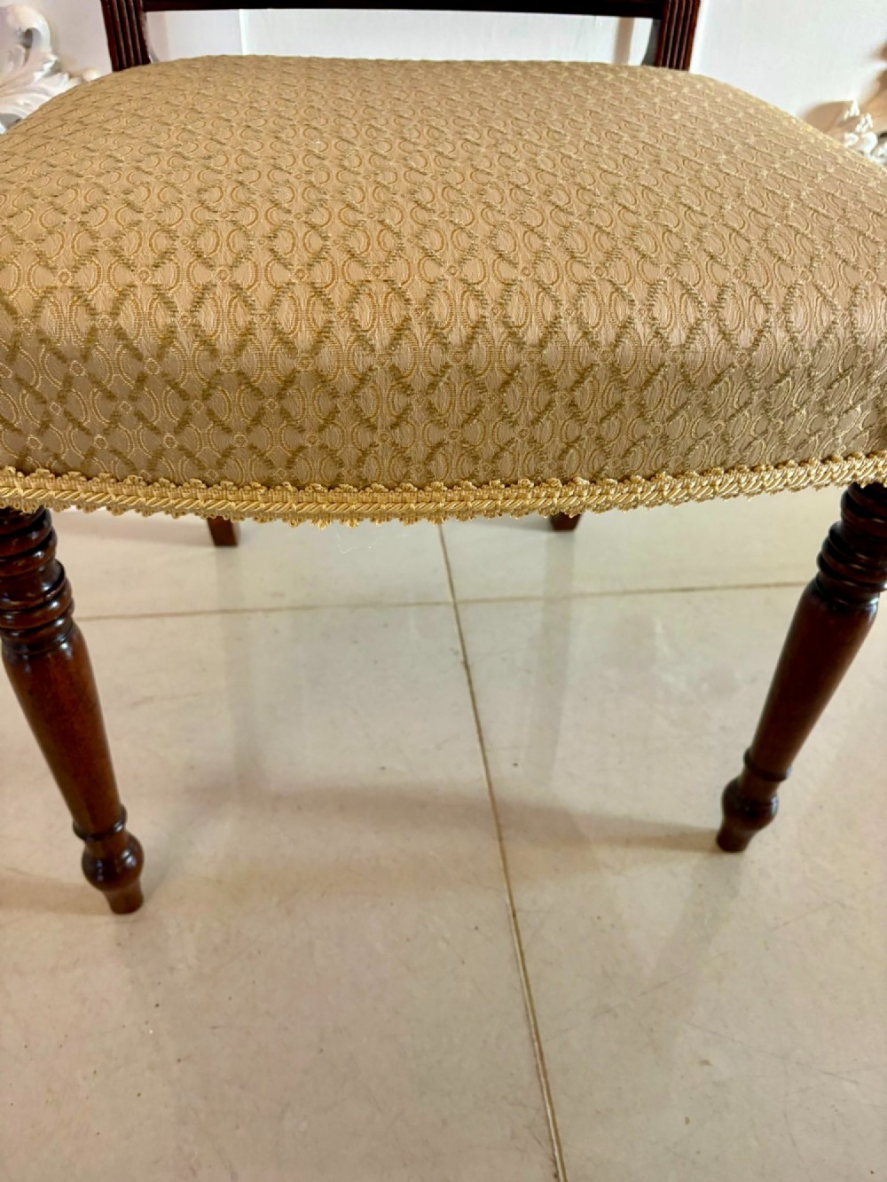 A set of eight George III style mahogany dining chairs featuring two carvers and six side chairs with reeded frames and patterned cream upholstered seats. View X