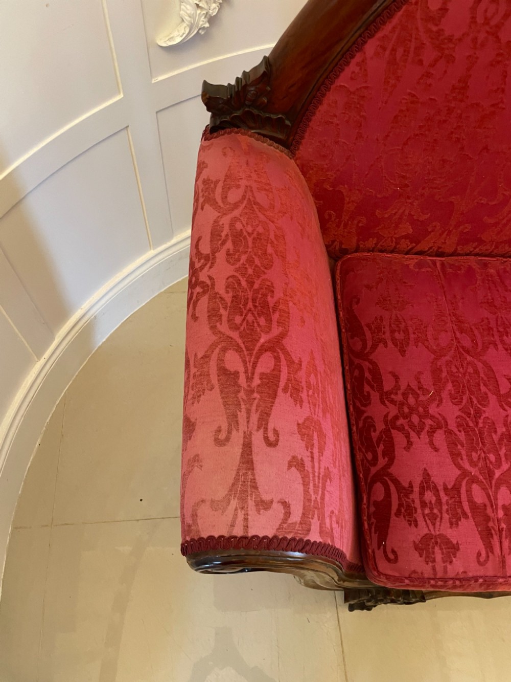 An antique Victorian carved mahogany chaise longue upholstered in deep red damask fabric with cabriole legs and ornate timber carving. View X