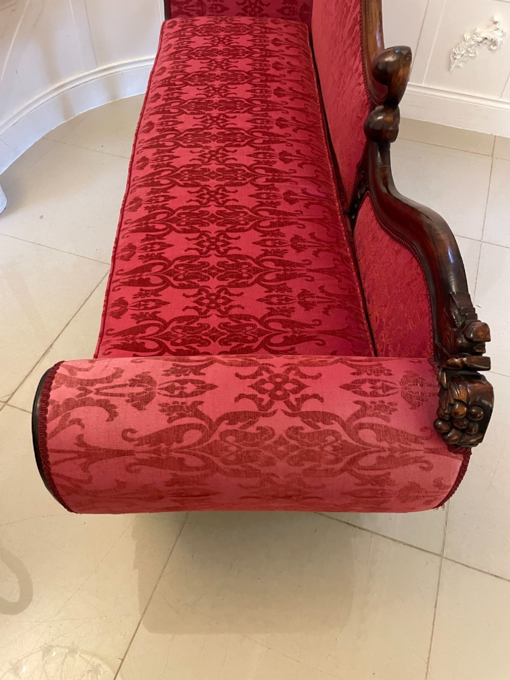 An antique Victorian carved mahogany chaise longue upholstered in deep red damask fabric with cabriole legs and ornate timber carving. View XIII