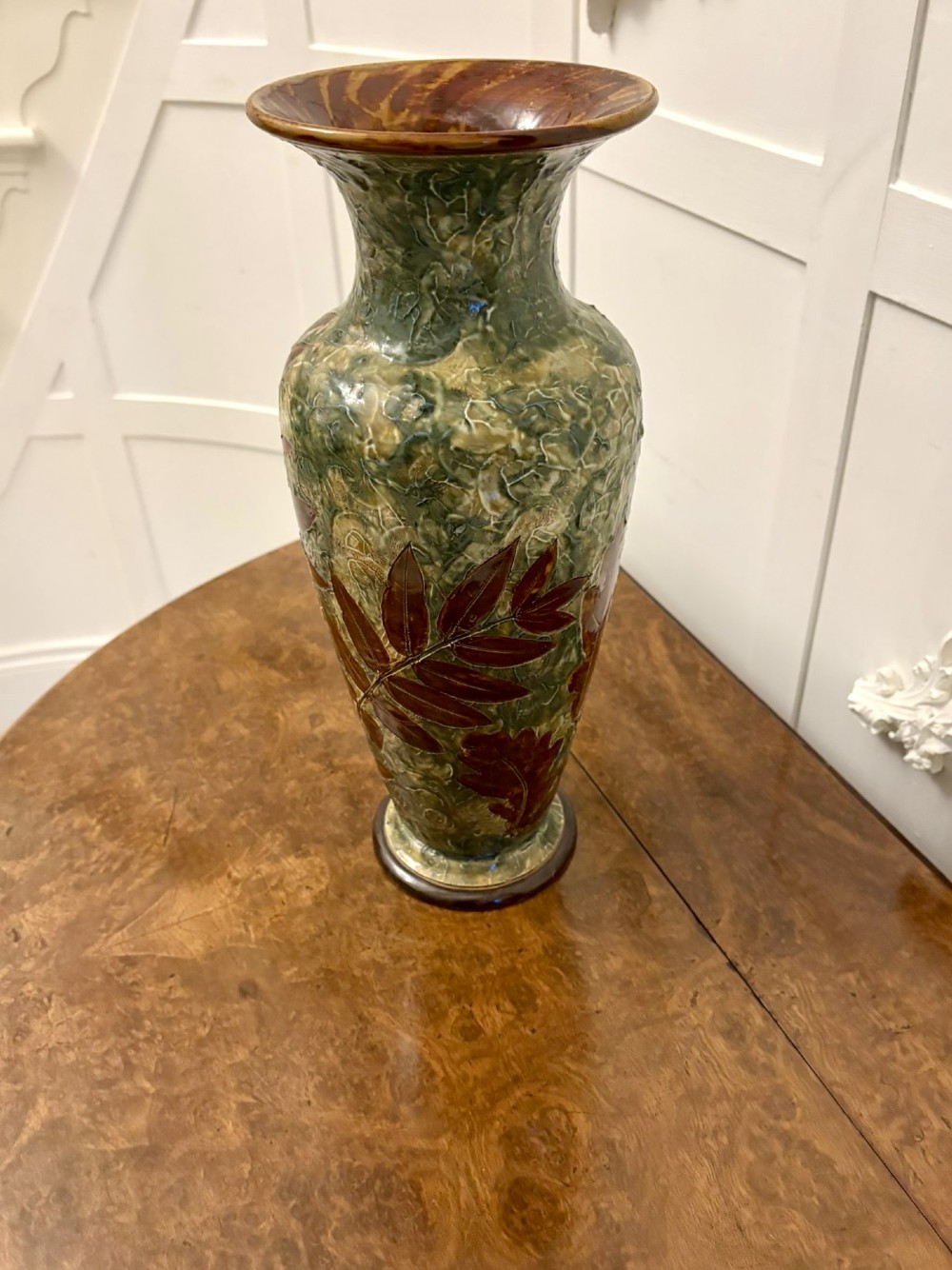 A tall Victorian glazed stoneware vase featuring a mottled green background decorated with brown leaf impressions and a flared rim. View VIII