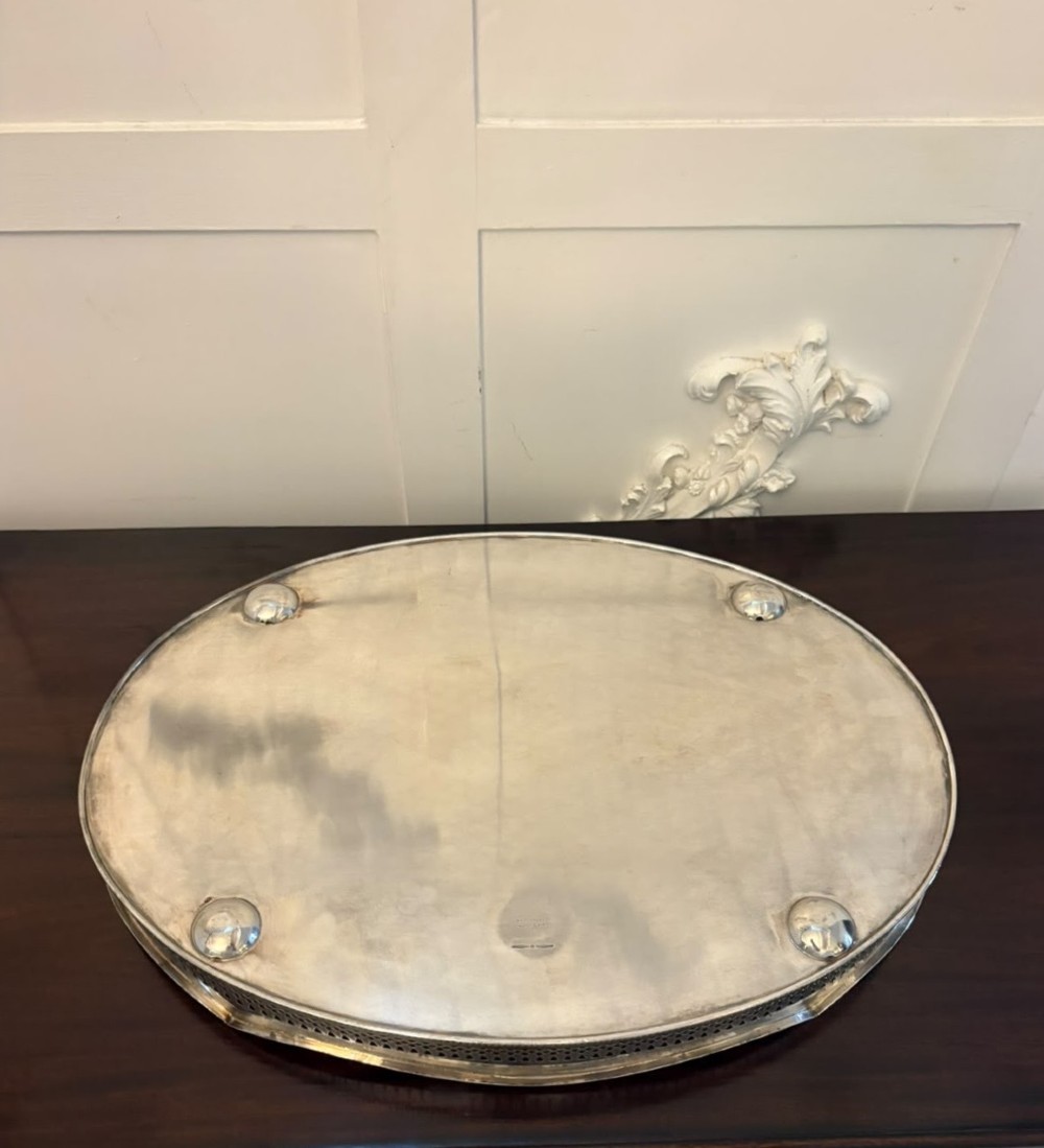 An oval Edwardian silver plated serving tray with an engraved foliate surface pattern and a pierced gallery border featuring cut-out hand grips. View VI
