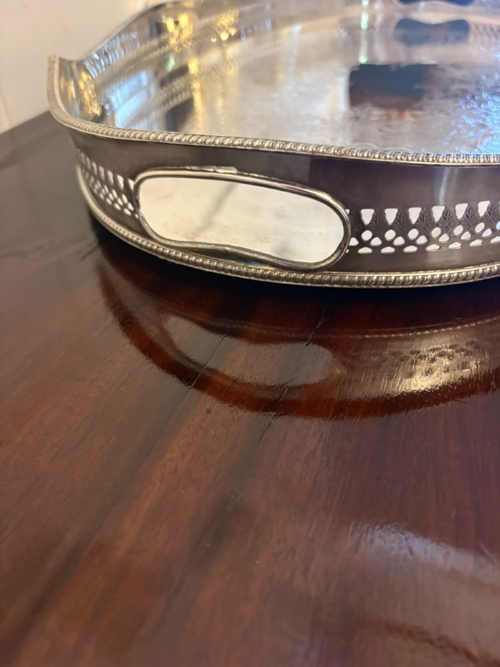 An oval Edwardian silver plated serving tray with an engraved foliate surface pattern and a pierced gallery border featuring cut-out hand grips. View IX