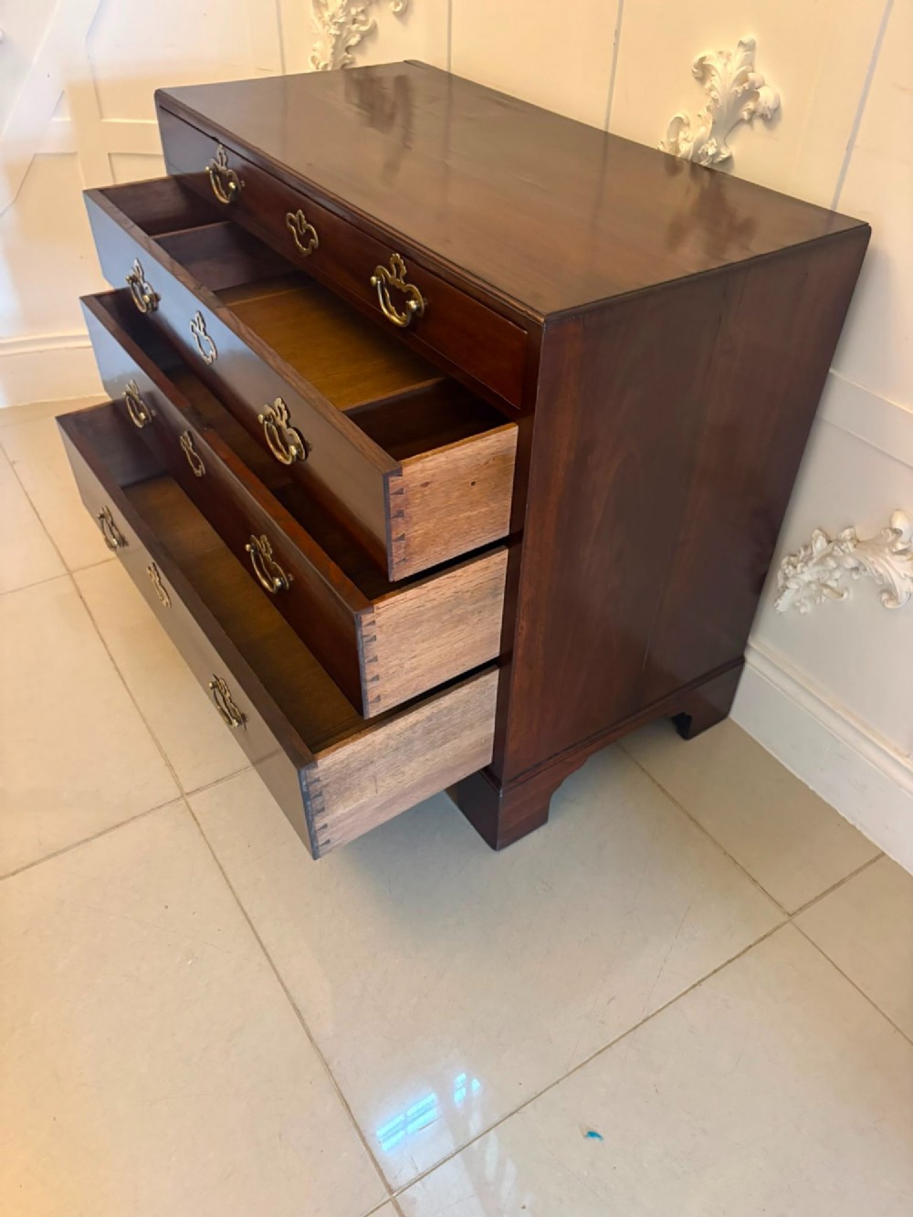 A George II mahogany chest of drawers featuring an open top writing drawer with an adjustable gilt-tooled green leather surface and brass handles. View V