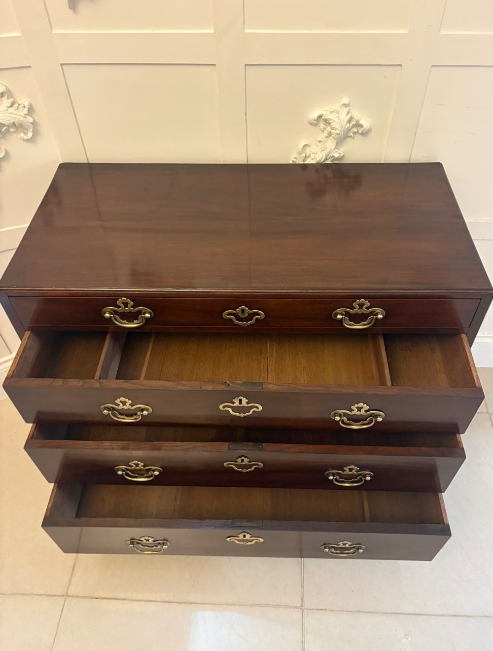 A George II mahogany chest of drawers featuring an open top writing drawer with an adjustable gilt-tooled green leather surface and brass handles. View VI
