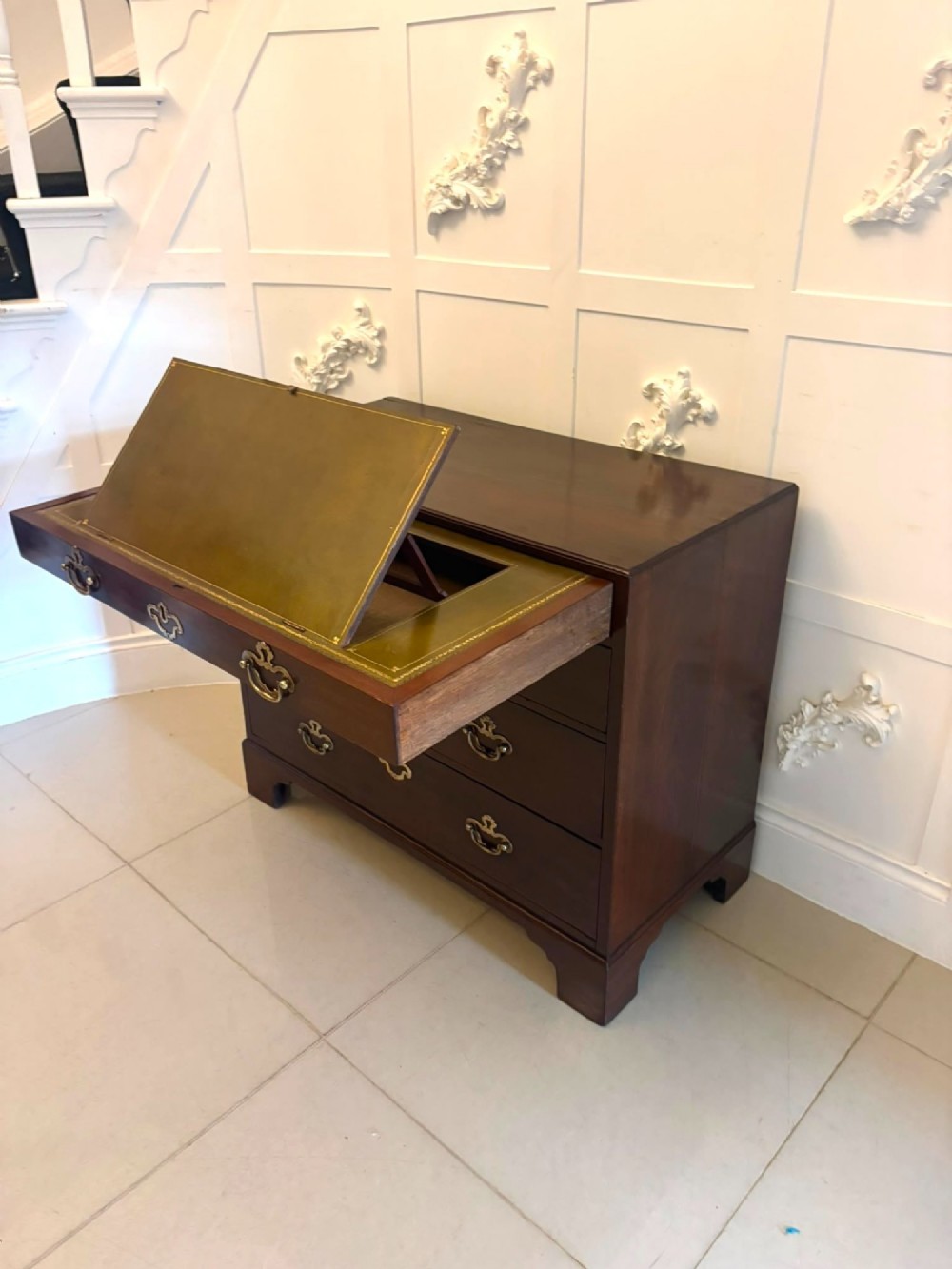 A George II mahogany chest of drawers featuring an open top writing drawer with an adjustable gilt-tooled green leather surface and brass handles. View XIV