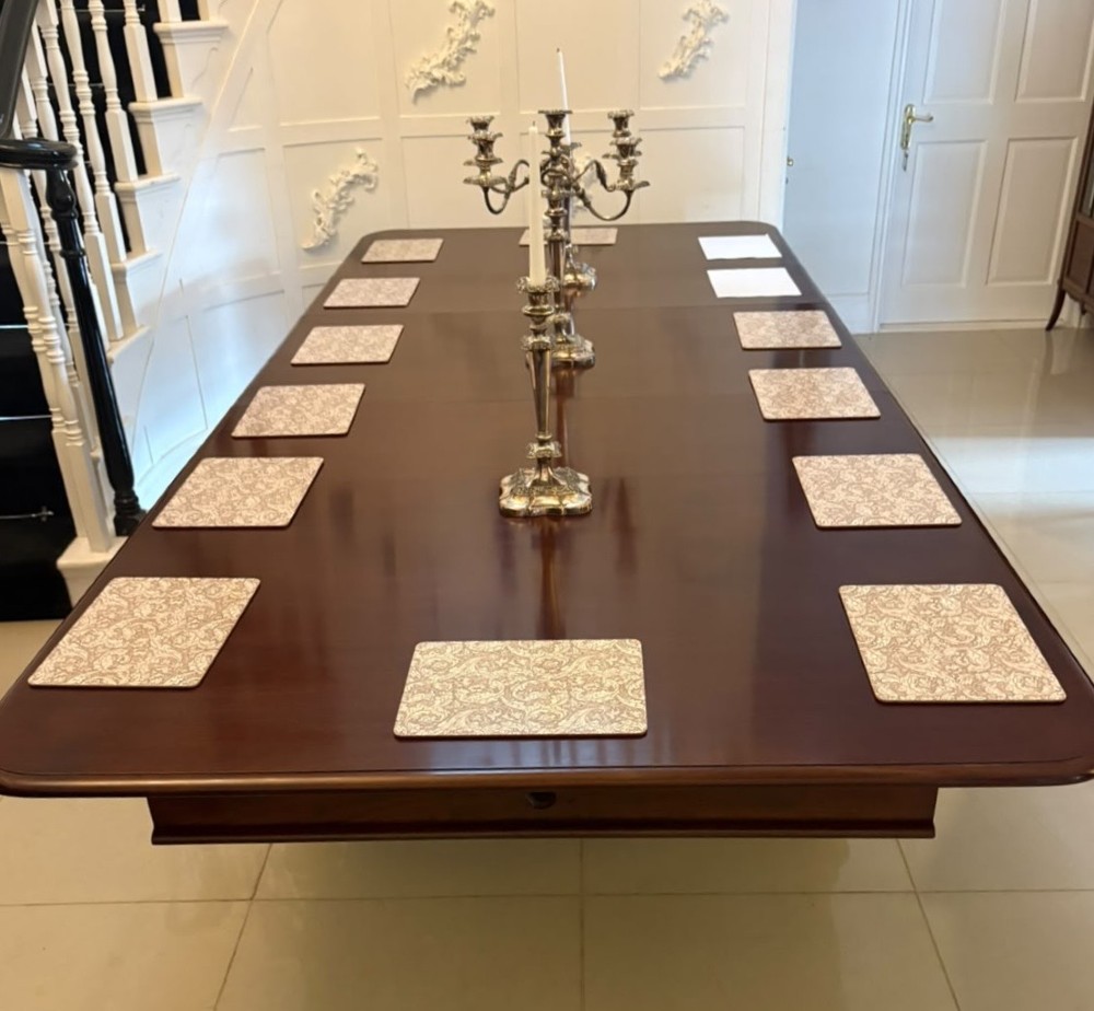 A large William IV figured mahogany extending dining table with a polished surface, rounded corners, and turned legs on brass castors. View II