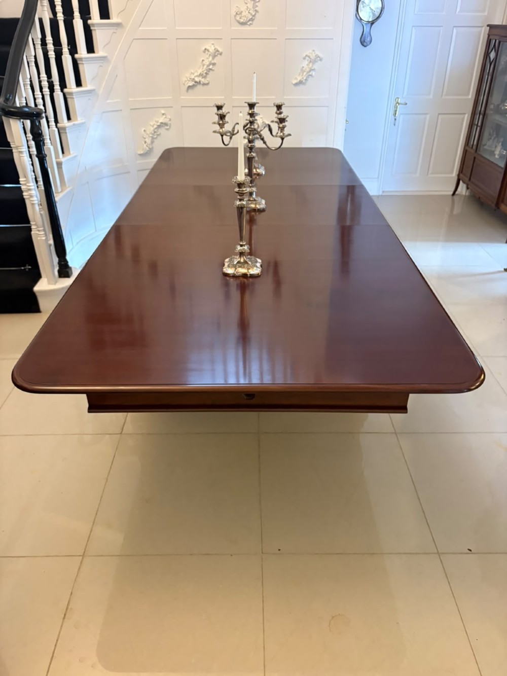 A large William IV figured mahogany extending dining table with a polished surface, rounded corners, and turned legs on brass castors. View IV