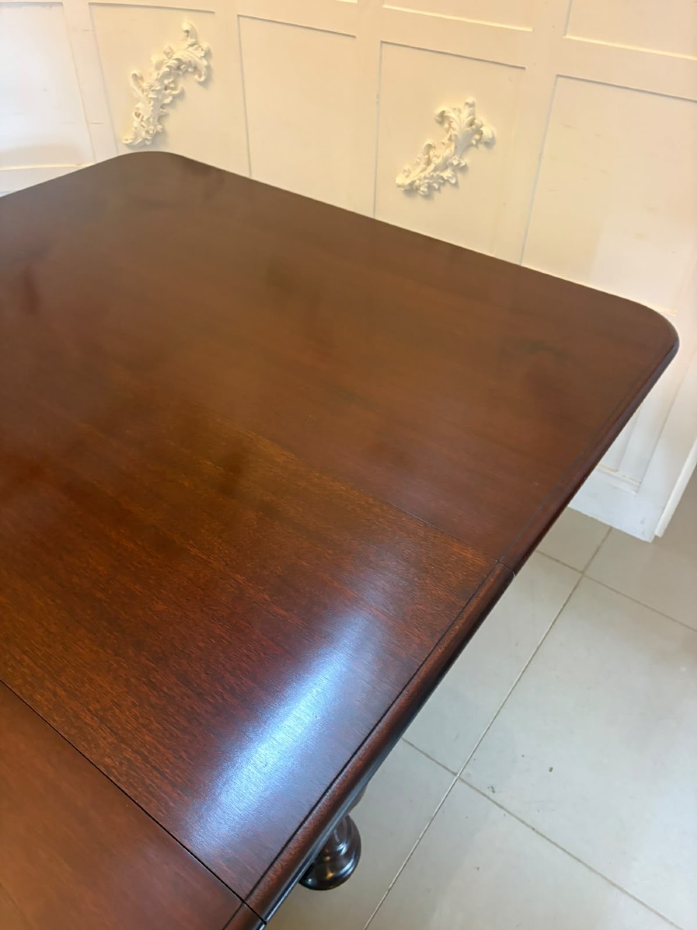 A large William IV figured mahogany extending dining table with a polished surface, rounded corners, and turned legs on brass castors. View V