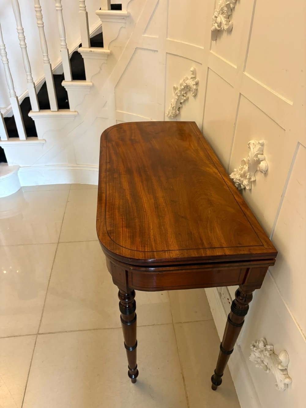 An antique Georgian mahogany fold-over card table featuring turned legs and subtle inlay stringing. View X