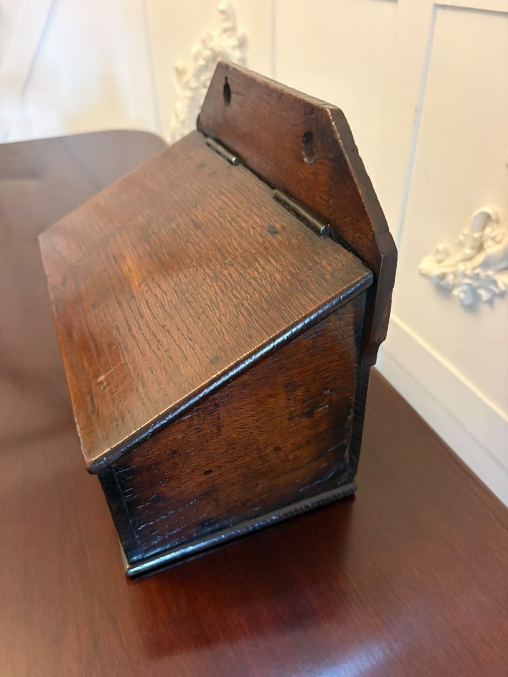 A dark oak Georgian wall-hanging candle box featuring a sloped hinged lid and a shaped backboard with two mounting holes. View VIII