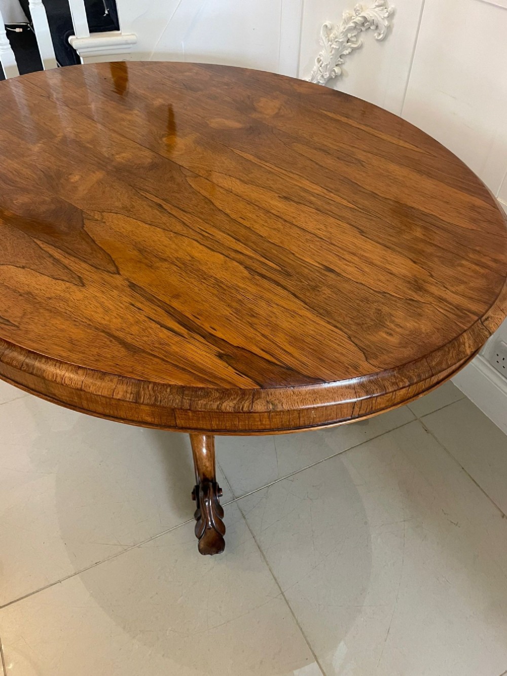 An antique Victorian rosewood tilt-top centre table shown with the circular top tilted vertically on a carved pedestal base. View V