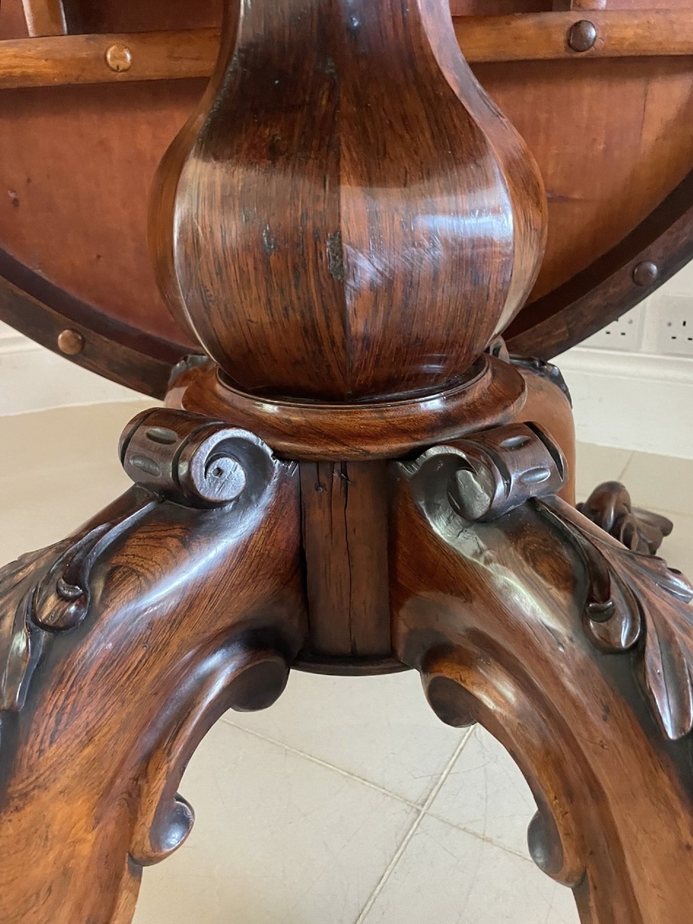 An antique Victorian rosewood tilt-top centre table shown with the circular top tilted vertically on a carved pedestal base. View VII
