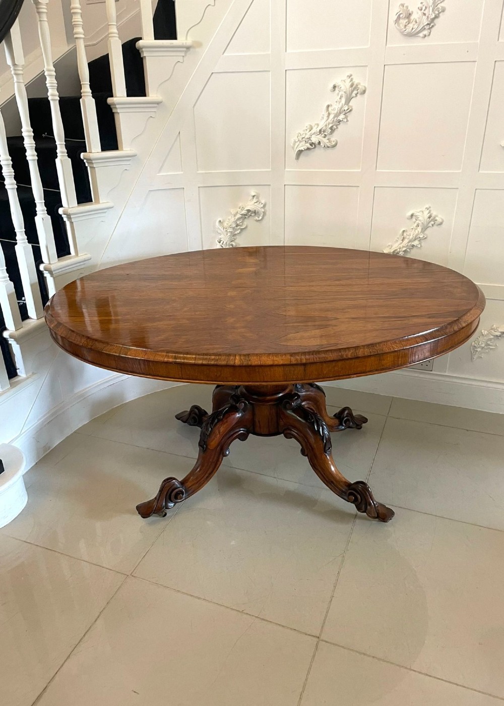 An antique Victorian rosewood tilt-top centre table shown with the circular top tilted vertically on a carved pedestal base. View IX