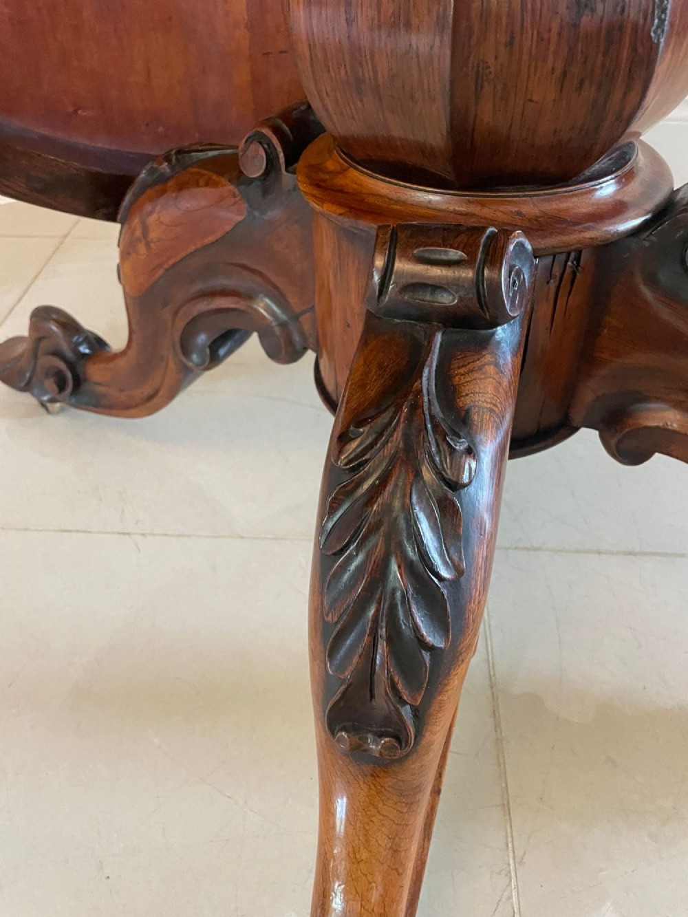 An antique Victorian rosewood tilt-top centre table shown with the circular top tilted vertically on a carved pedestal base. View XI