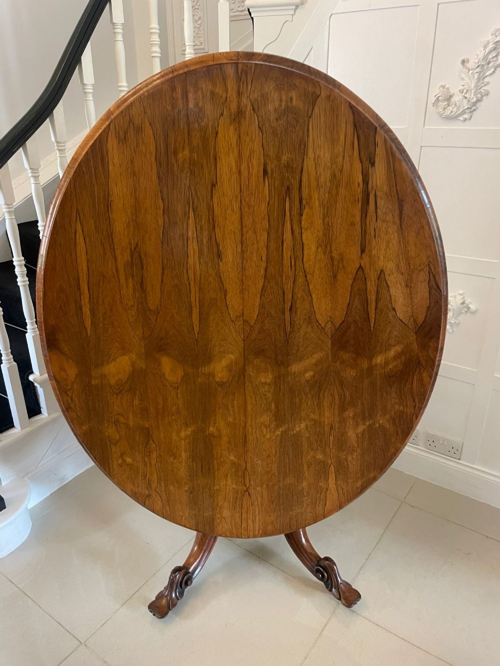 An antique Victorian rosewood tilt-top centre table shown with the circular top tilted vertically on a carved pedestal base. View XIII
