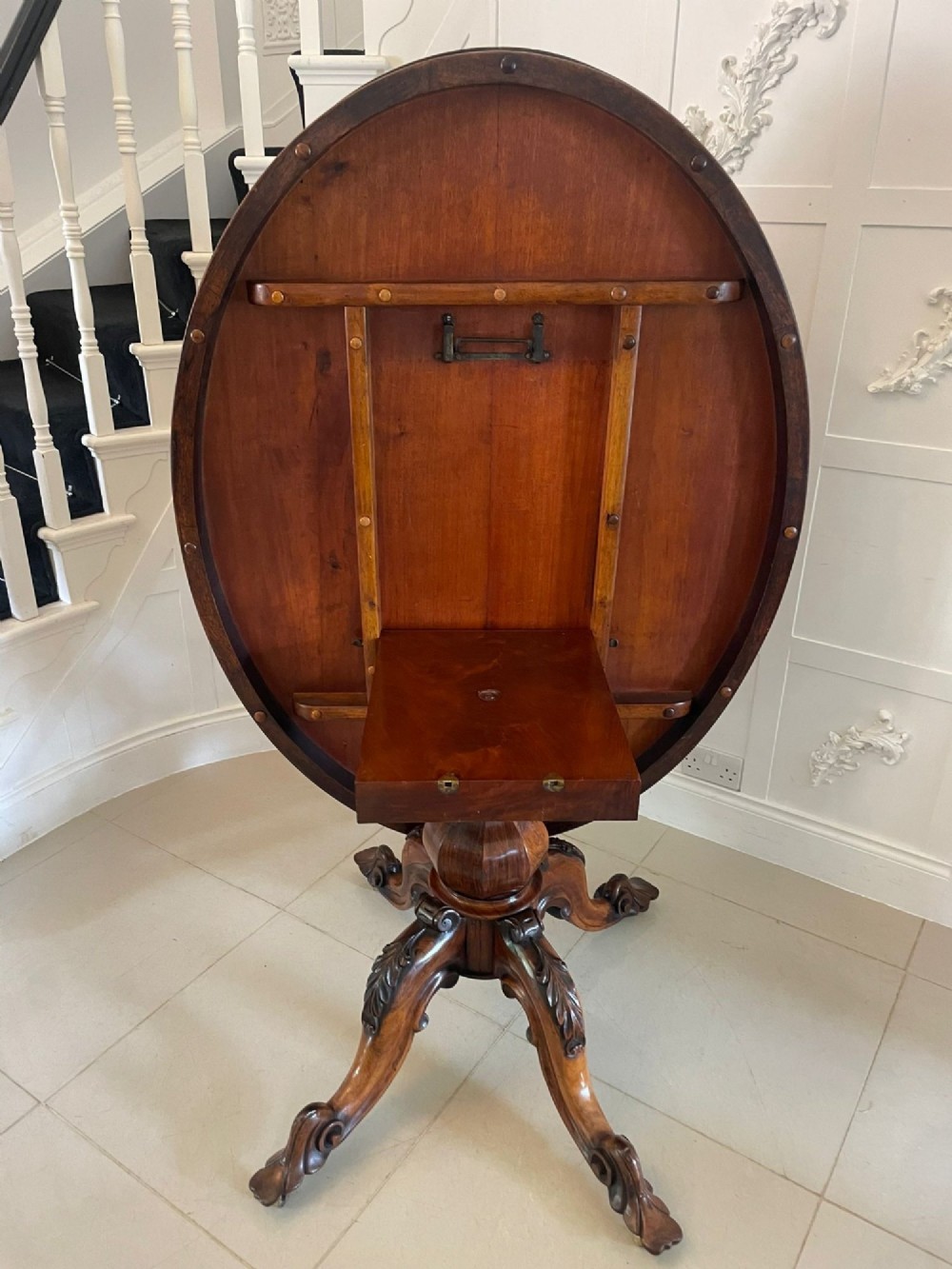 An antique Victorian rosewood tilt-top centre table shown with the circular top tilted vertically on a carved pedestal base. View XIV