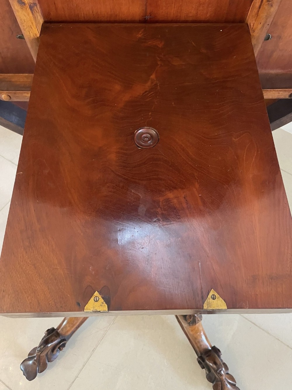 An antique Victorian rosewood tilt-top centre table shown with the circular top tilted vertically on a carved pedestal base. View XV