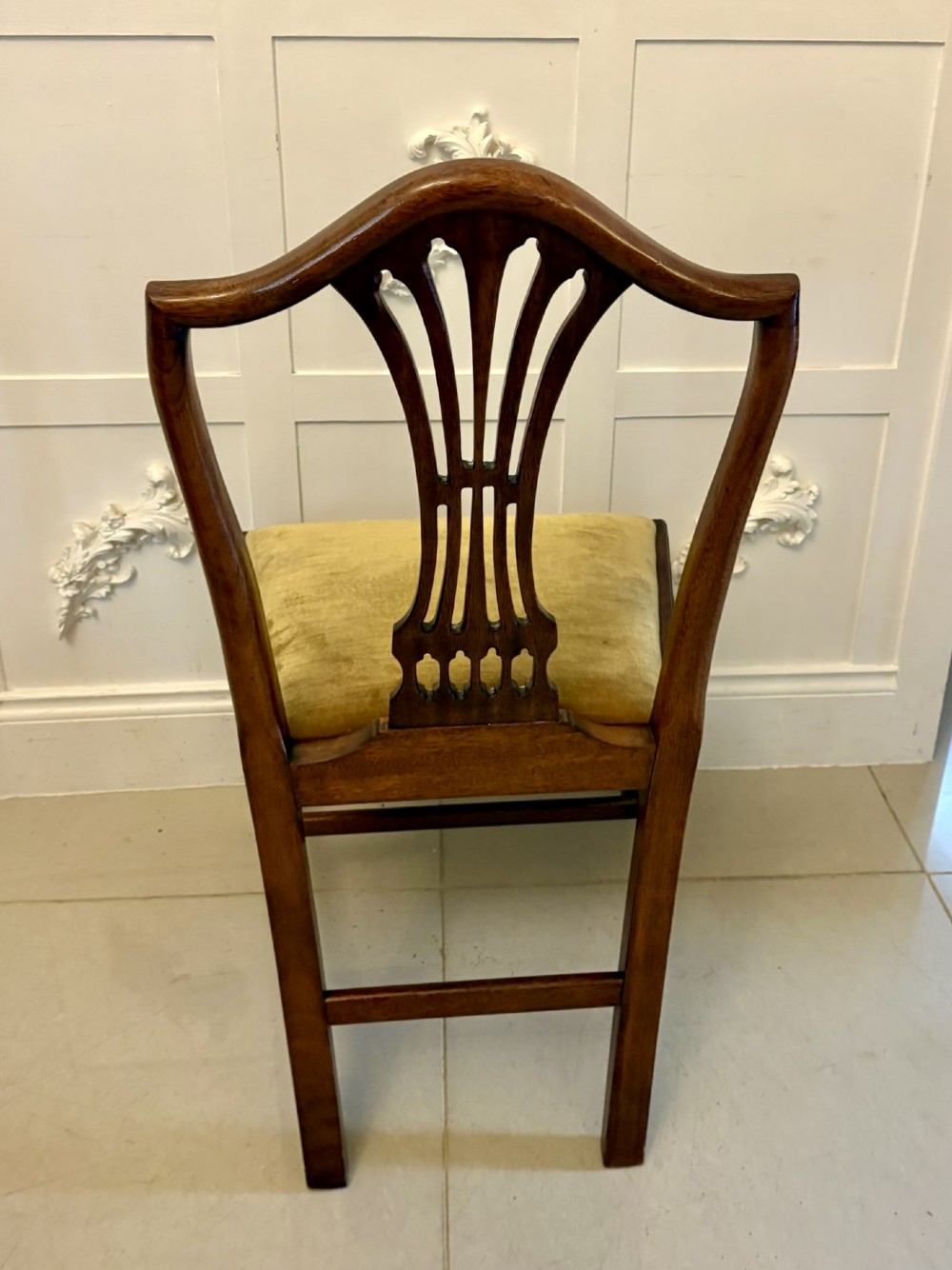 A set of twelve mahogany Hepplewhite style dining chairs featuring shield backs with carved splats and gold velvet drop-in seats. View III