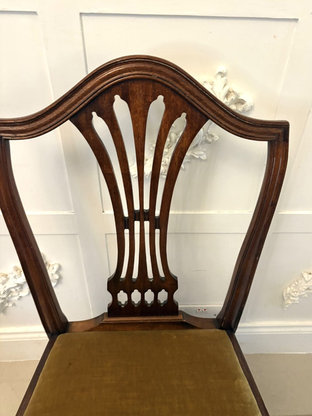 A set of twelve mahogany Hepplewhite style dining chairs featuring shield backs with carved splats and gold velvet drop-in seats. View X
