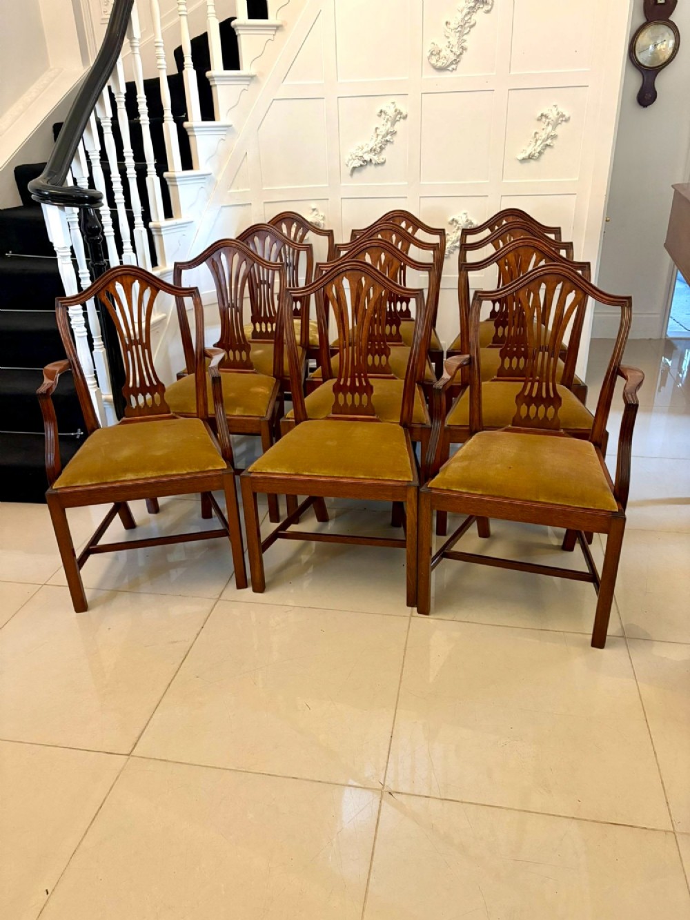 A set of twelve mahogany Hepplewhite style dining chairs featuring shield backs with carved splats and gold velvet drop-in seats.