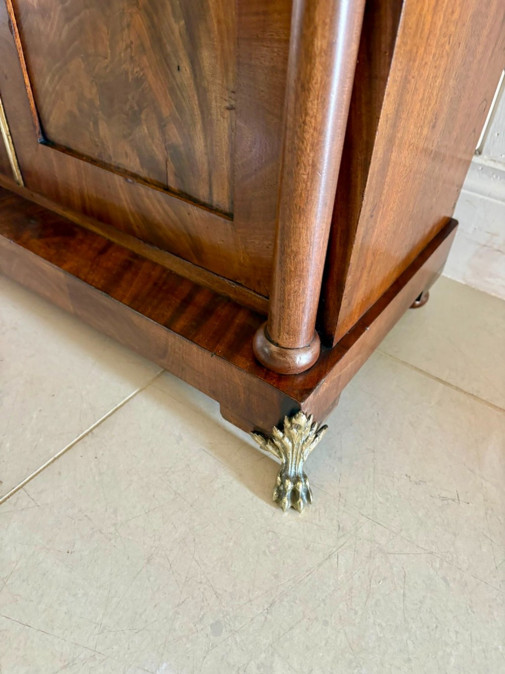 An antique Regency mahogany chiffonier cabinet featuring flame mahogany double doors, turned side columns, diamond detailing, and metal claw feet. View VII
