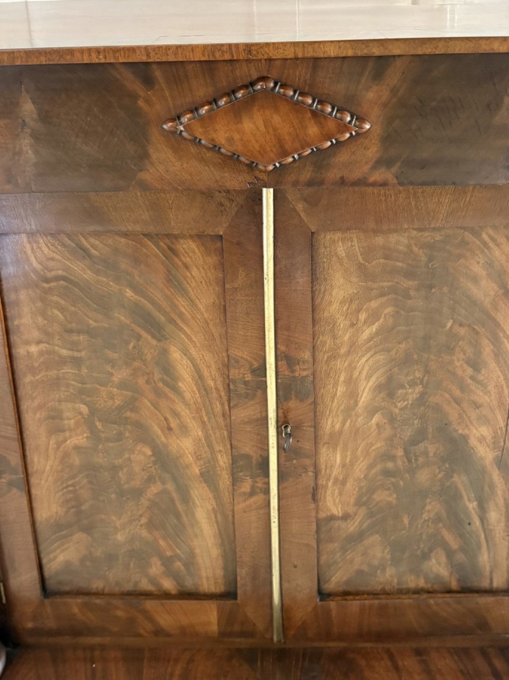 An antique Regency mahogany chiffonier cabinet featuring flame mahogany double doors, turned side columns, diamond detailing, and metal claw feet. View XI