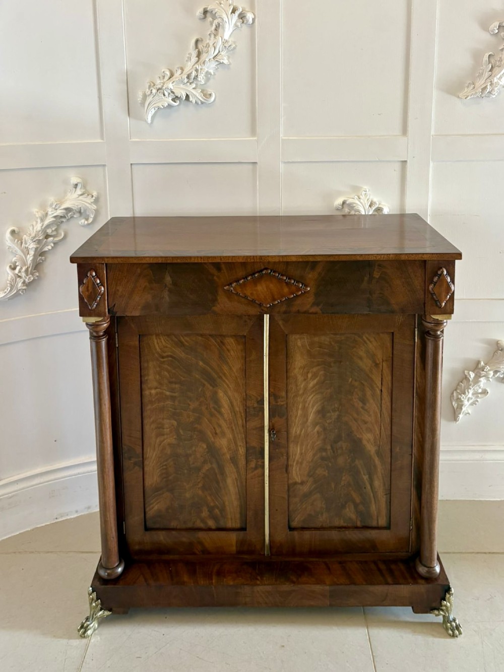 An antique Regency mahogany chiffonier cabinet featuring flame mahogany double doors, turned side columns, diamond detailing, and metal claw feet. View XII