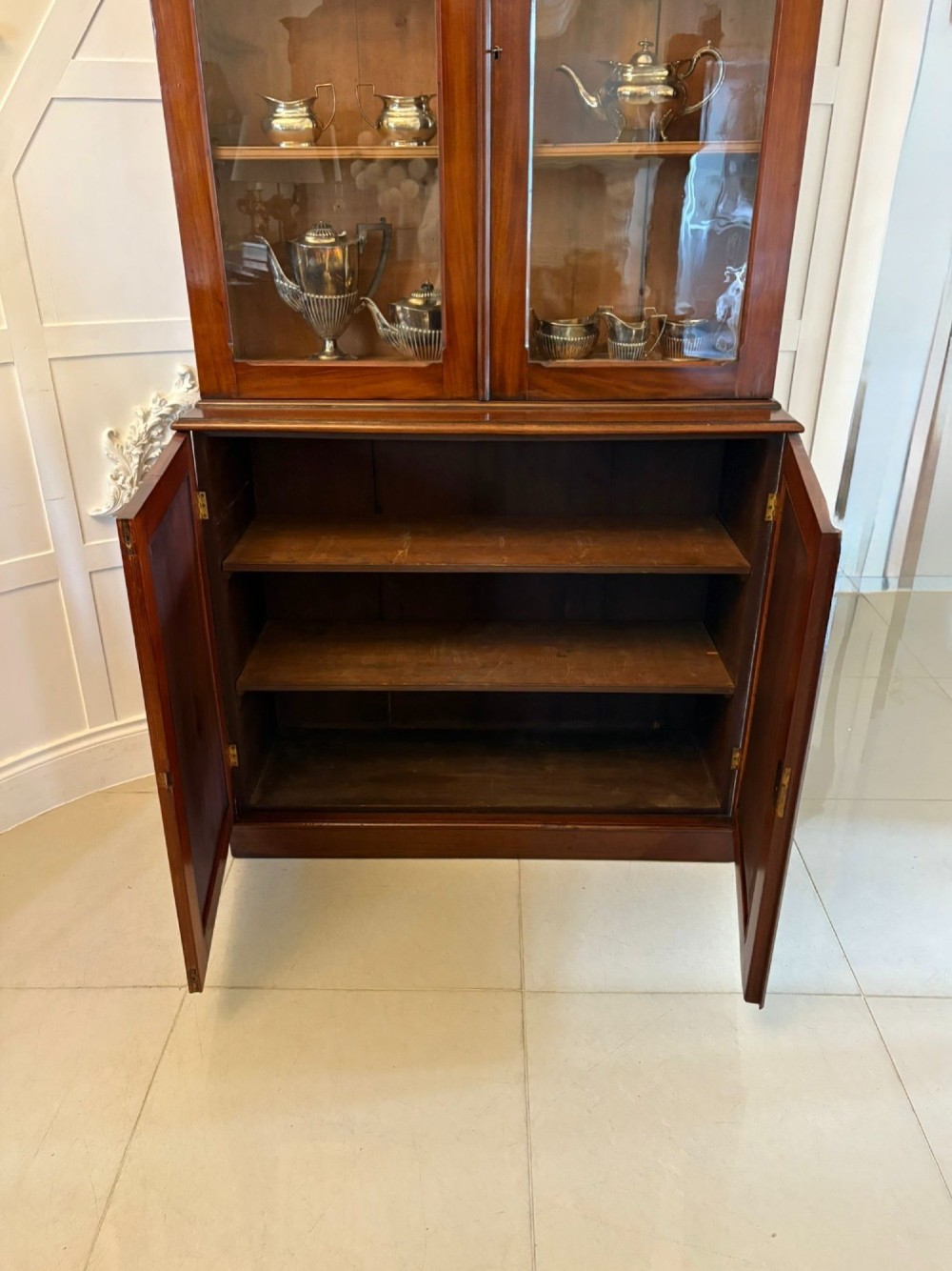An antique Victorian mahogany bookcase featuring two upper glass-glazed doors and two lower flame mahogany panelled cupboard doors. View II