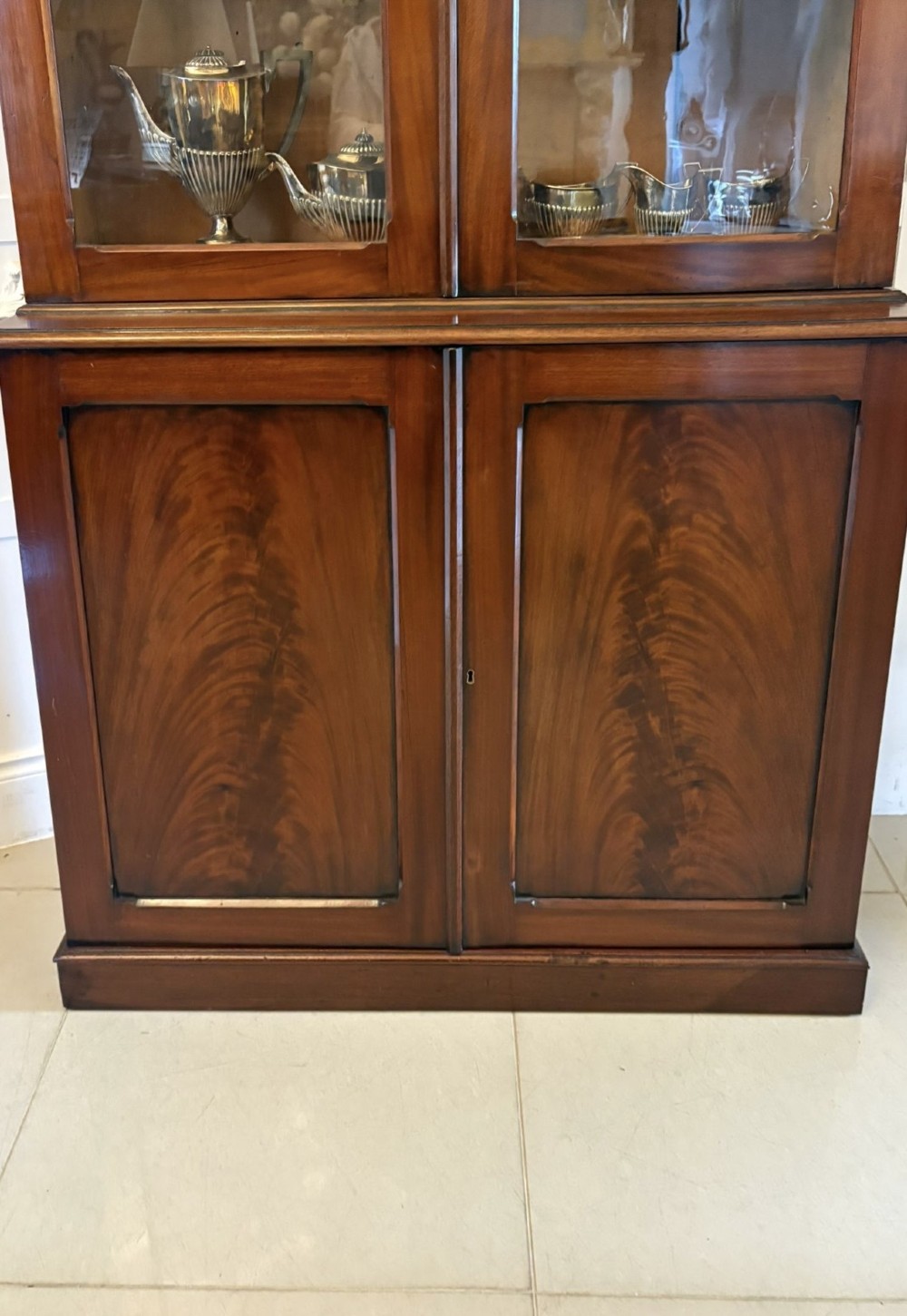 An antique Victorian mahogany bookcase featuring two upper glass-glazed doors and two lower flame mahogany panelled cupboard doors. View VI