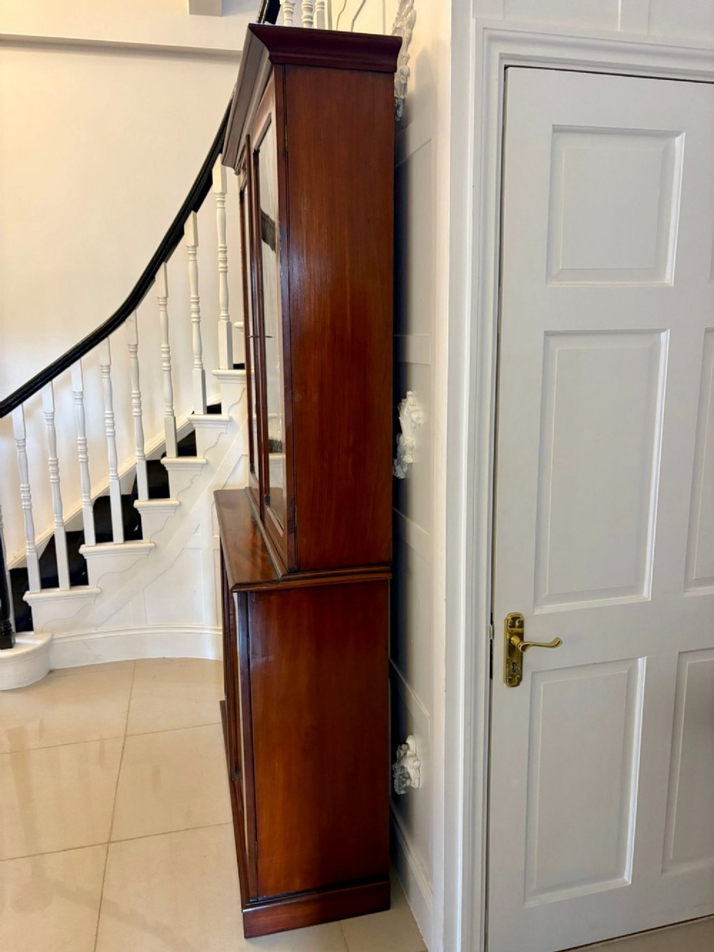 An antique Victorian mahogany bookcase featuring two upper glass-glazed doors and two lower flame mahogany panelled cupboard doors. View VII