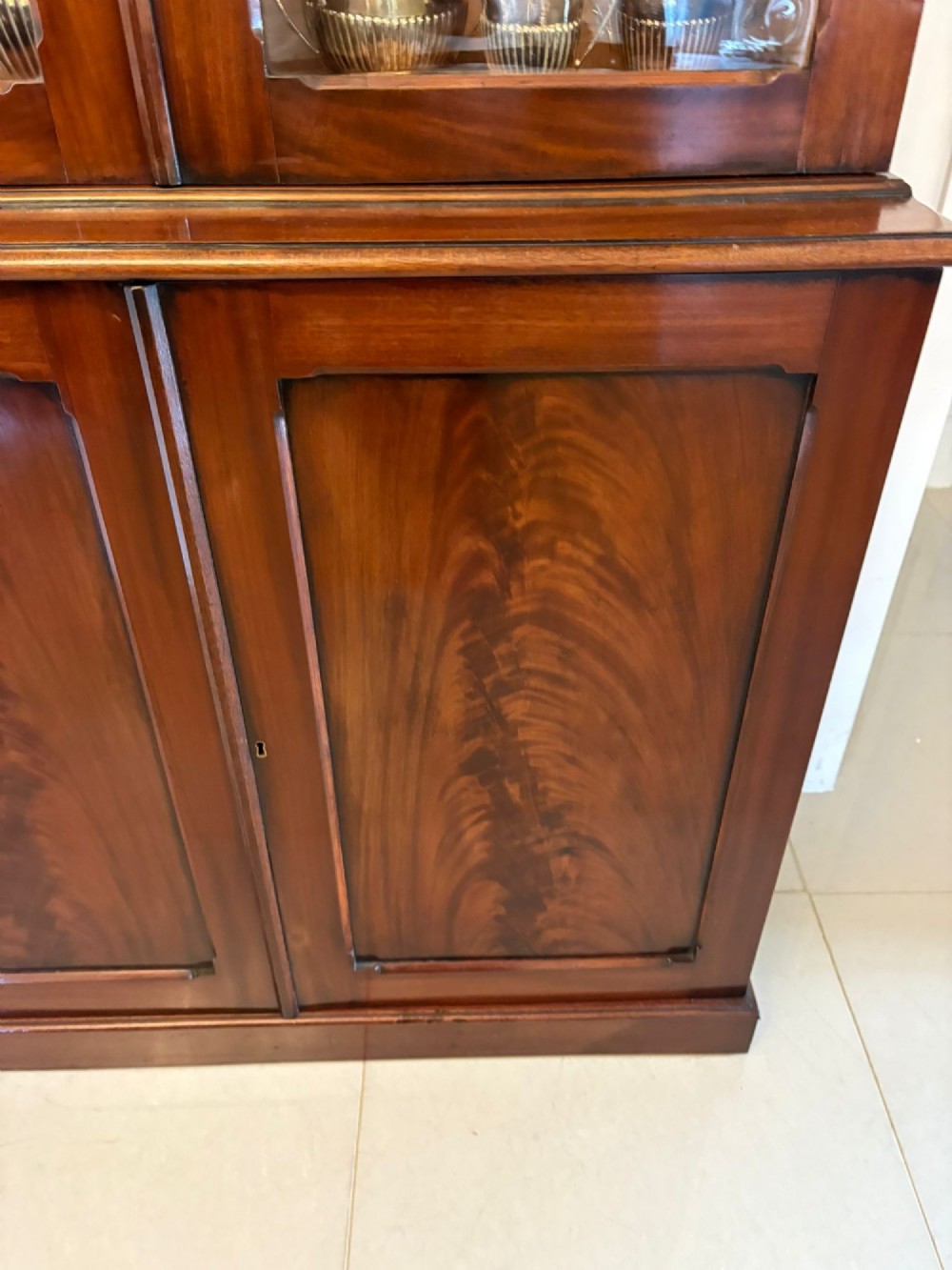 An antique Victorian mahogany bookcase featuring two upper glass-glazed doors and two lower flame mahogany panelled cupboard doors. View IX