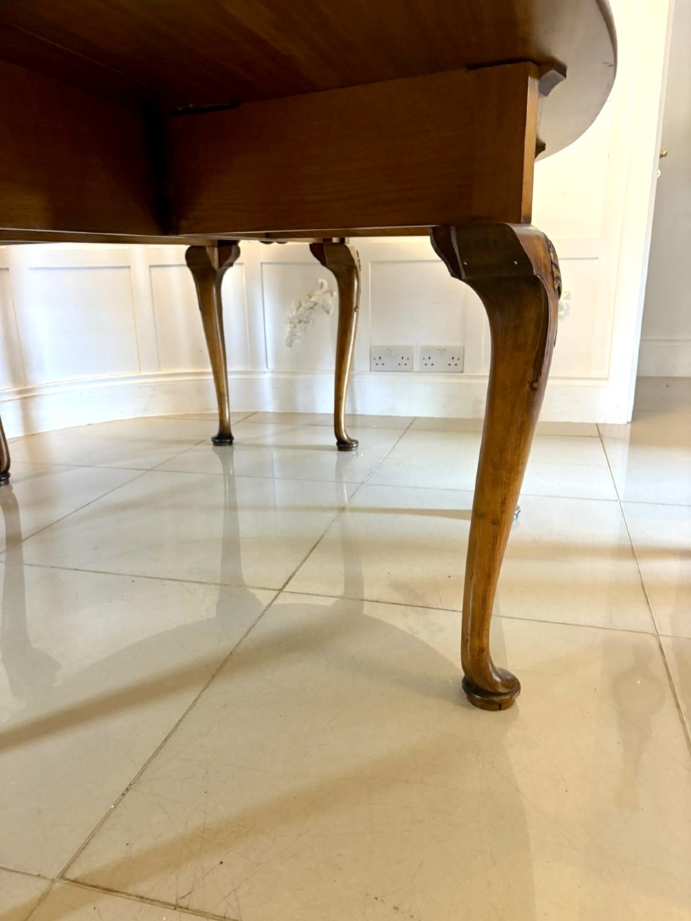A large oval figured walnut wake dining table featuring drop leaves and cabriole legs ending in pad feet. View V
