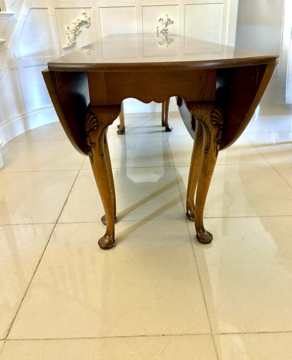 A large oval figured walnut wake dining table featuring drop leaves and cabriole legs ending in pad feet. View XII