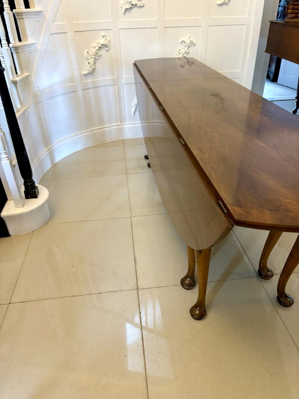 A large oval figured walnut wake dining table featuring drop leaves and cabriole legs ending in pad feet. View XIII
