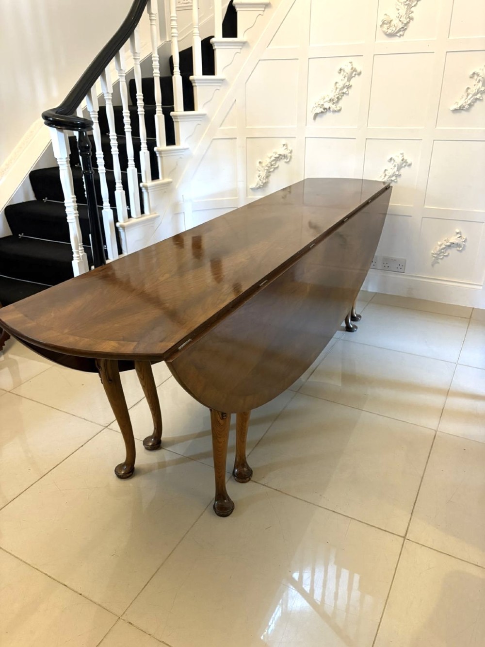 A large oval figured walnut wake dining table featuring drop leaves and cabriole legs ending in pad feet. View XIV