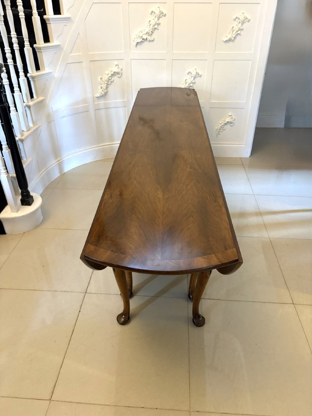 A large oval figured walnut wake dining table featuring drop leaves and cabriole legs ending in pad feet. View XV