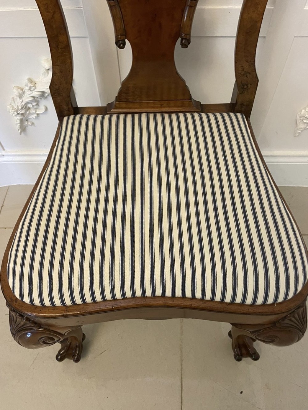 A set of twelve Victorian burr walnut dining chairs with carved splat backs, cabriole legs, and black and white striped upholstered seats. View VI