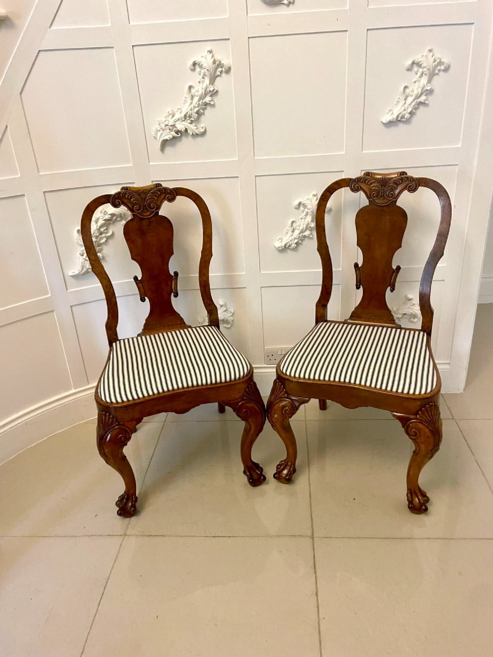 A set of twelve Victorian burr walnut dining chairs with carved splat backs, cabriole legs, and black and white striped upholstered seats. View XII