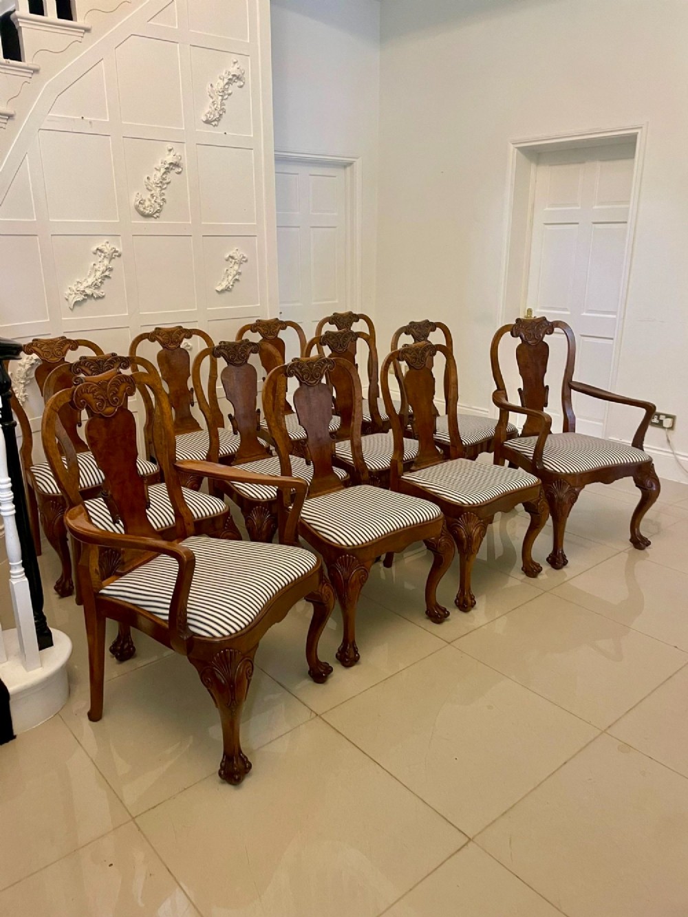 A set of twelve Victorian burr walnut dining chairs with carved splat backs, cabriole legs, and black and white striped upholstered seats. View XIII