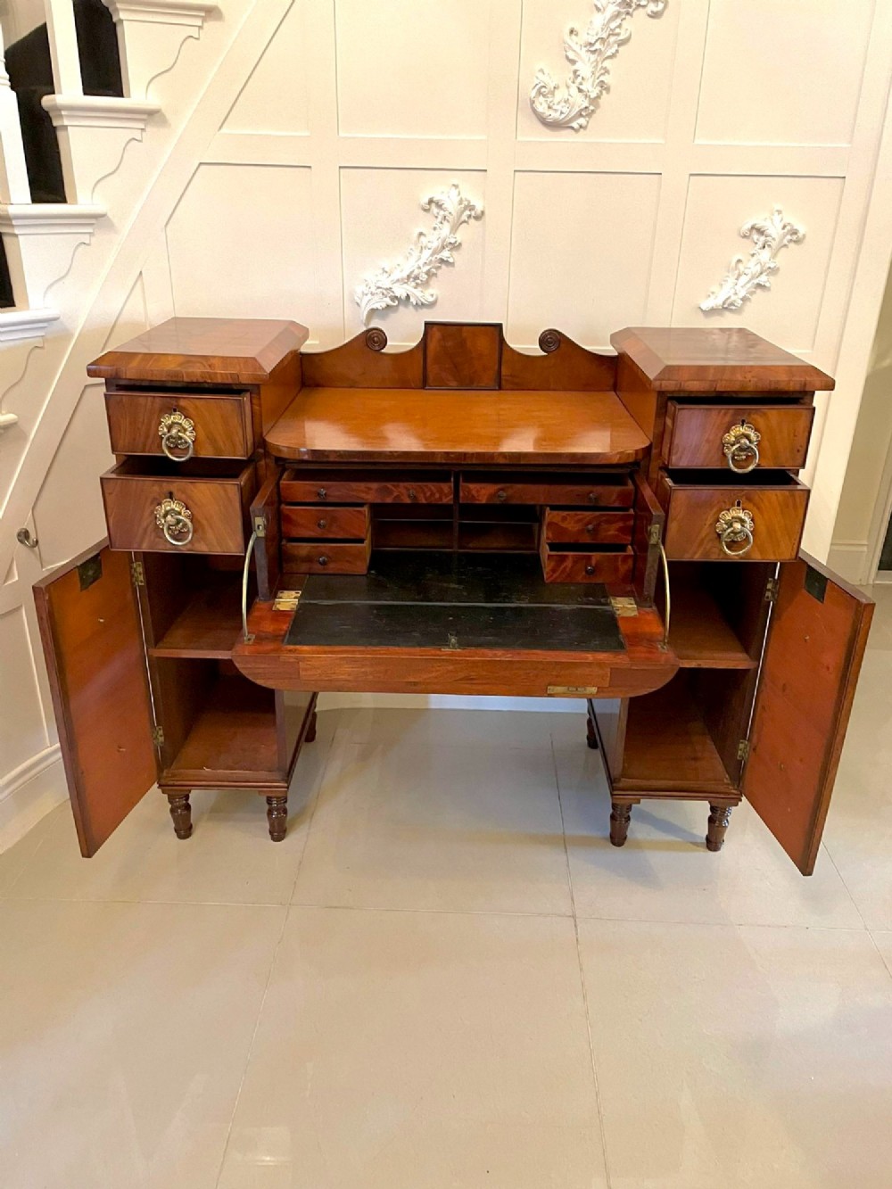 An antique Regency mahogany secretaire sideboard featuring twin pedestals, multiple drawers with brass ring pulls, and a scrolled backboard gallery. View IX