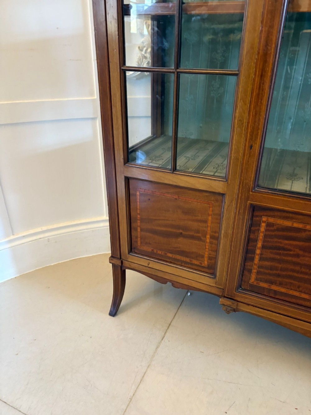 An Edwardian inlaid mahogany display cabinet featuring three glazed doors with decorative glazing bars and a fabric-lined interior. View II